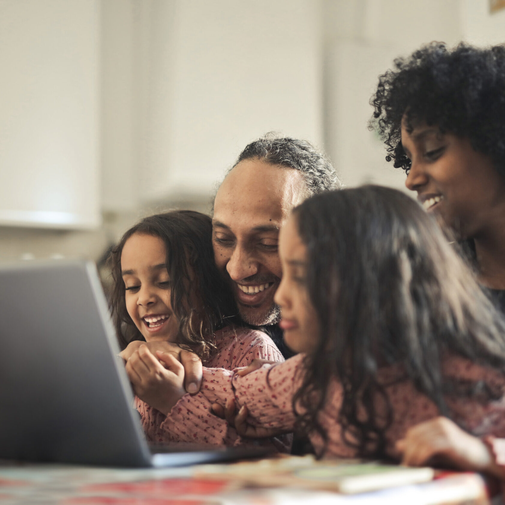 family smiles in front of a laptop